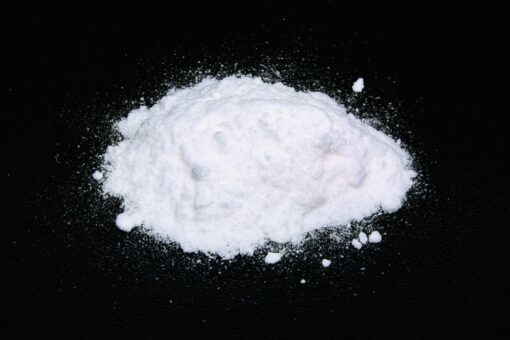 Close-up image of fine ketamine powder in a container, showcasing its smooth texture and high purity.