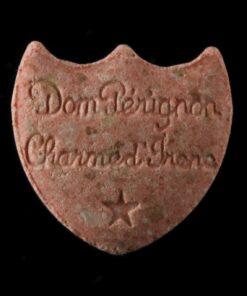 Close-up image of Dom Perignon MDMA pills with a champagne logo imprint, showcasing their premium quality and vibrant colors.