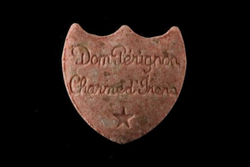 Close-up image of Dom Perignon MDMA pills with a champagne logo imprint, showcasing their premium quality and vibrant colors.