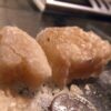 A close-up of Crystal MDMA (Molly) in its pure crystalline form, displayed on a white surface.