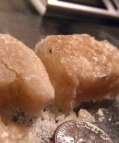 A close-up of Crystal MDMA (Molly) in its pure crystalline form, displayed on a white surface.